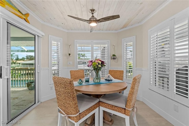 dining space with wooden ceiling, crown molding, a wainscoted wall, and light wood finished floors