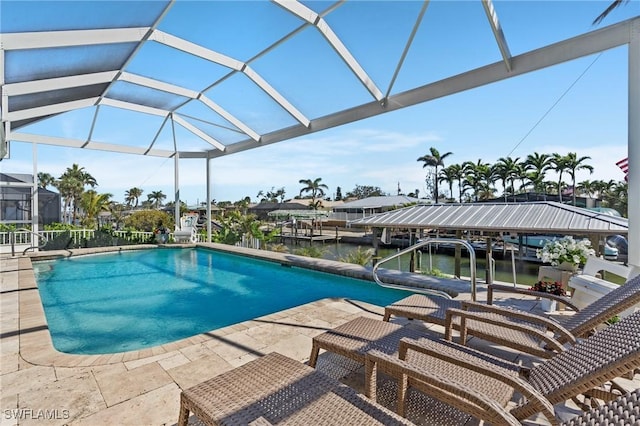 pool featuring glass enclosure, a patio, and a water view