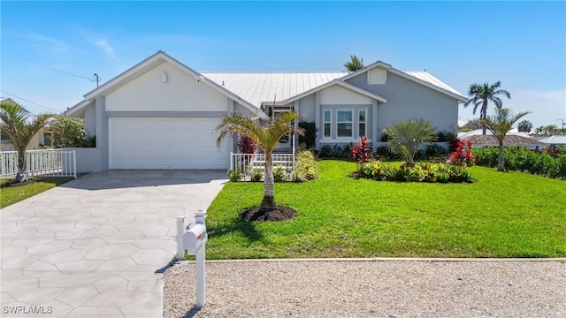 ranch-style home featuring driveway, fence, metal roof, a front yard, and a garage