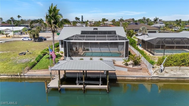 dock area with glass enclosure, a yard, an outdoor pool, a water view, and boat lift