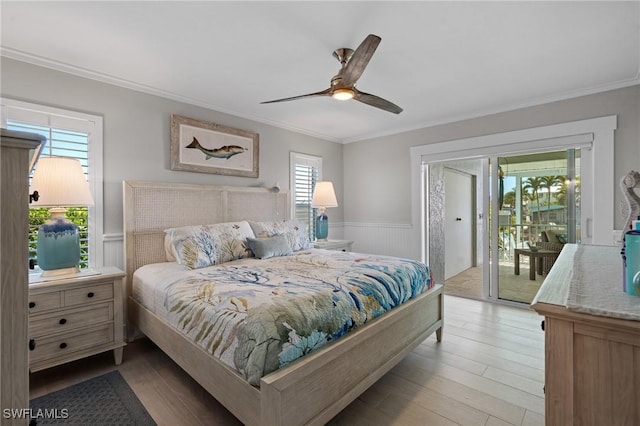 bedroom featuring a wainscoted wall, light wood-style floors, ornamental molding, and access to outside