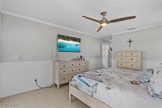 bedroom with visible vents, light wood-style flooring, wainscoting, and ornamental molding