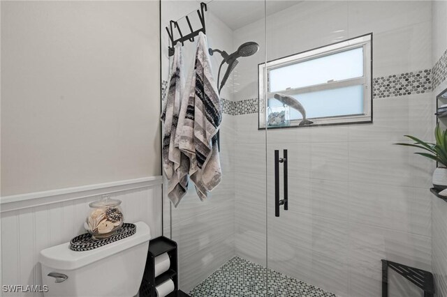 bathroom featuring wainscoting, a stall shower, and toilet