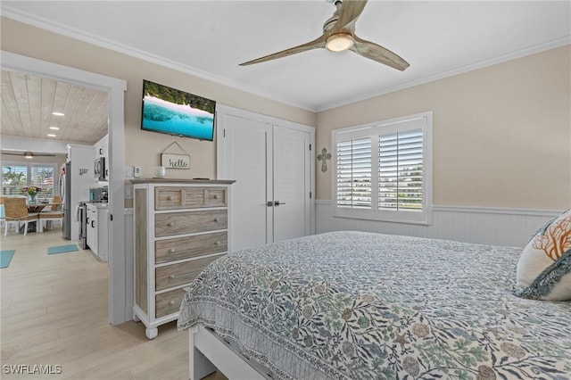 bedroom with light wood finished floors, freestanding refrigerator, wainscoting, and crown molding