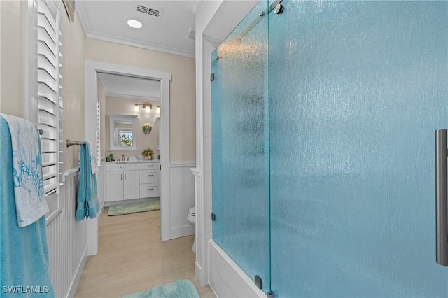 bathroom featuring visible vents, crown molding, toilet, a shower with shower door, and vanity