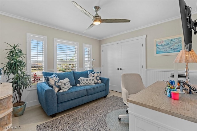 office featuring a wainscoted wall, light wood-style flooring, crown molding, and ceiling fan