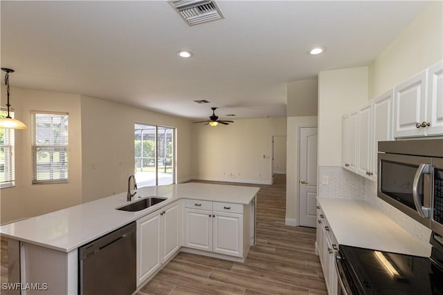 12391 Muddy Creek Ln, Fort Myers, FL 33913 - kitchen with stainless steel appliances, light wood-style floors, light countertops, ceiling fan, and white cabinetry