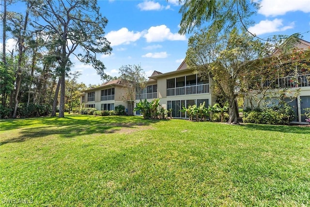 rear view of property featuring stucco siding, a yard, and a sunroom