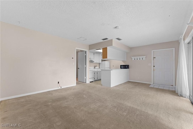 unfurnished living room featuring a textured ceiling, baseboards, visible vents, and light carpet