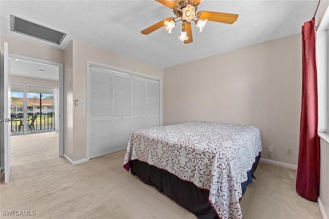 bedroom with visible vents, baseboards, light colored carpet, a closet, and a textured ceiling