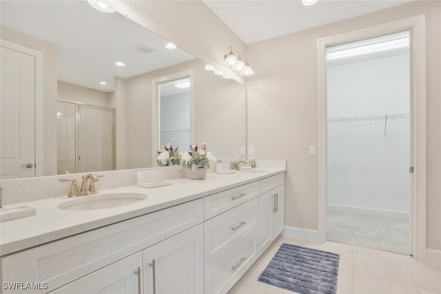 full bathroom featuring a spacious closet, tile patterned floors, a sink, and a stall shower