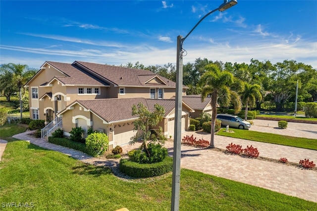 view of front of house with stucco siding, an attached garage, decorative driveway, and a front yard