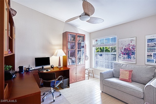 office area featuring light wood finished floors, baseboards, lofted ceiling, and ceiling fan