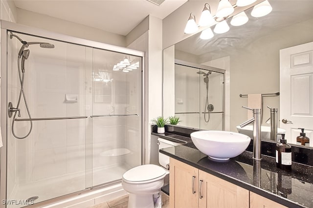 bathroom featuring tile patterned flooring, vanity, a shower stall, and toilet