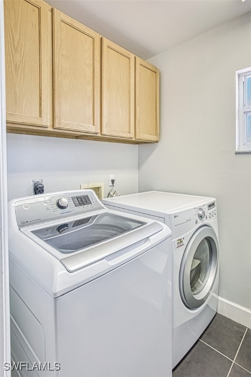 laundry room featuring washer and dryer, dark tile patterned floors, cabinet space, and baseboards