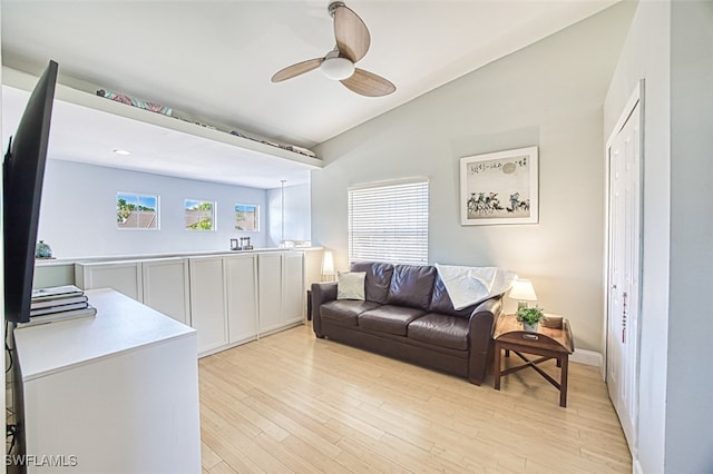 living room featuring light wood-style flooring, a ceiling fan, and vaulted ceiling