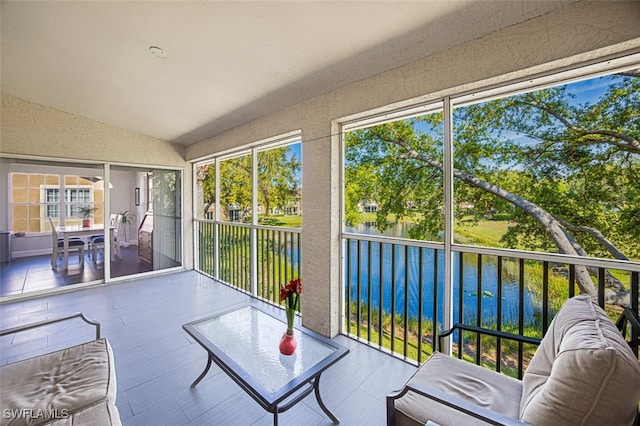 sunroom featuring vaulted ceiling, a healthy amount of sunlight, and a water view