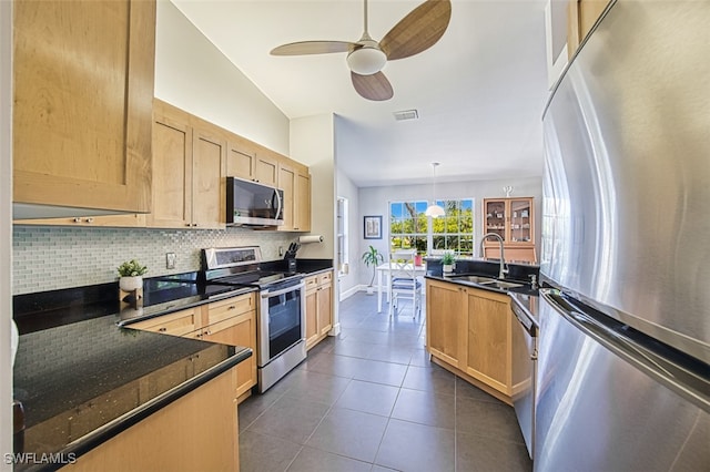 kitchen featuring tasteful backsplash, light brown cabinets, stainless steel appliances, and a sink