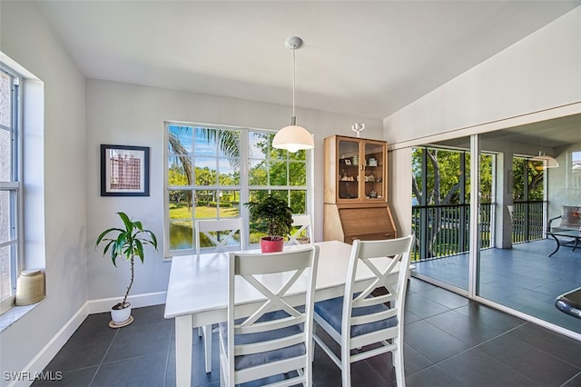 dining room with lofted ceiling, dark tile patterned flooring, and baseboards