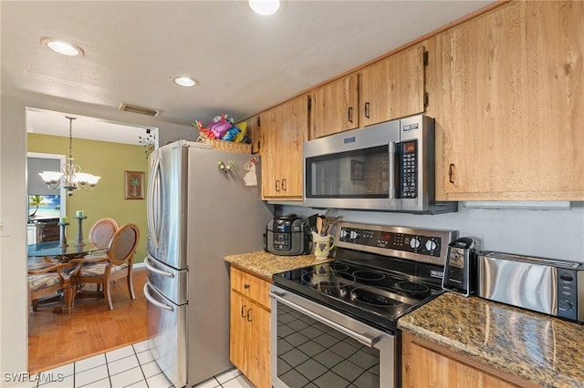 kitchen with visible vents, a chandelier, light stone counters, appliances with stainless steel finishes, and light tile patterned flooring