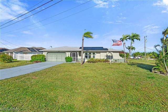 ranch-style home featuring fence, driveway, an attached garage, a front lawn, and roof mounted solar panels