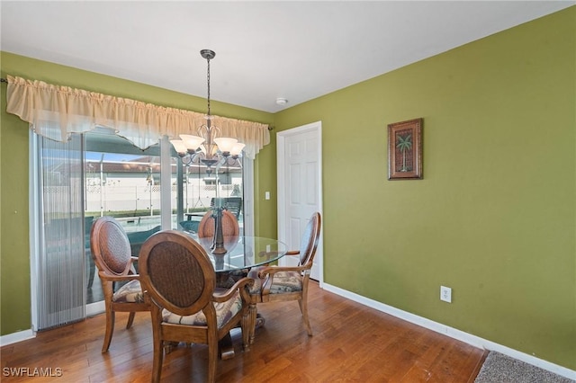 dining room featuring an inviting chandelier, wood finished floors, and baseboards