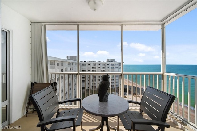 sunroom / solarium featuring a beach view and a water view