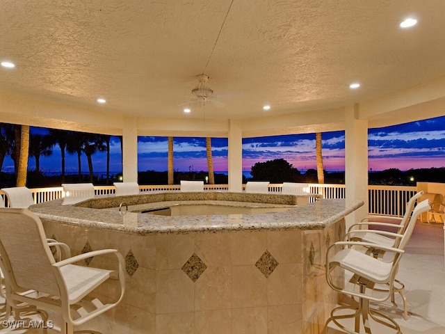 patio terrace at dusk featuring outdoor dry bar and ceiling fan