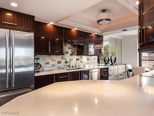 kitchen featuring light countertops, ornamental molding, decorative backsplash, stainless steel appliances, and a sink