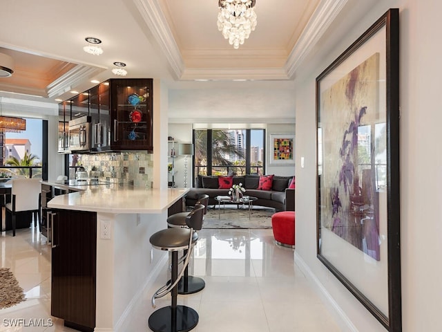 bar featuring decorative backsplash, a tray ceiling, light tile patterned floors, and crown molding