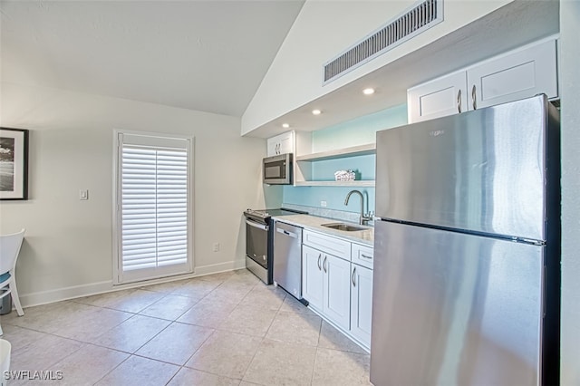 kitchen with visible vents, light tile patterned flooring, a sink, vaulted ceiling, and appliances with stainless steel finishes