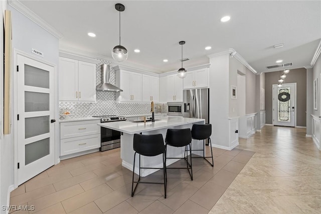 kitchen with ornamental molding, stainless steel appliances, light countertops, white cabinets, and wall chimney range hood