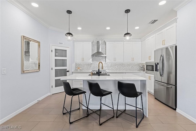 kitchen with visible vents, appliances with stainless steel finishes, light countertops, and wall chimney range hood