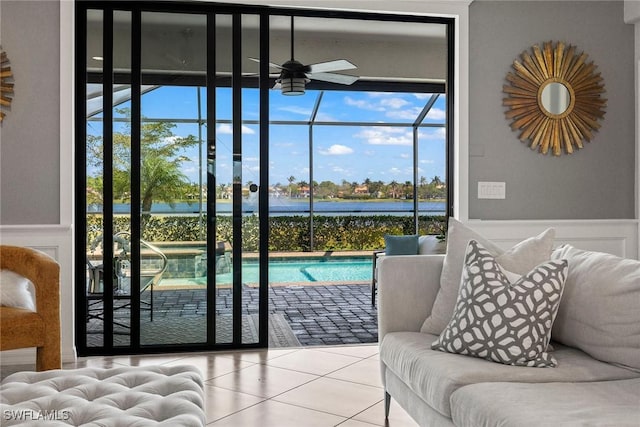 doorway to outside featuring tile patterned flooring, a water view, a ceiling fan, and a sunroom