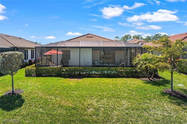 rear view of property featuring a lanai, a lawn, and a tile roof