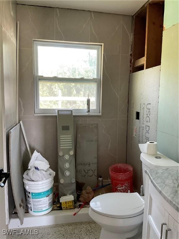 bathroom with speckled floor, toilet, and vanity