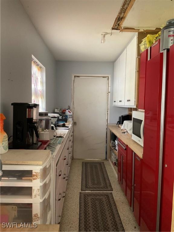 kitchen featuring white microwave, light countertops, and white cabinetry