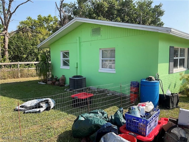 view of side of property with a yard, fence, and cooling unit