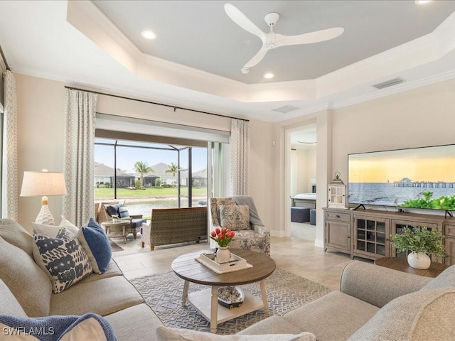 living area with visible vents, ornamental molding, a ceiling fan, a tray ceiling, and recessed lighting