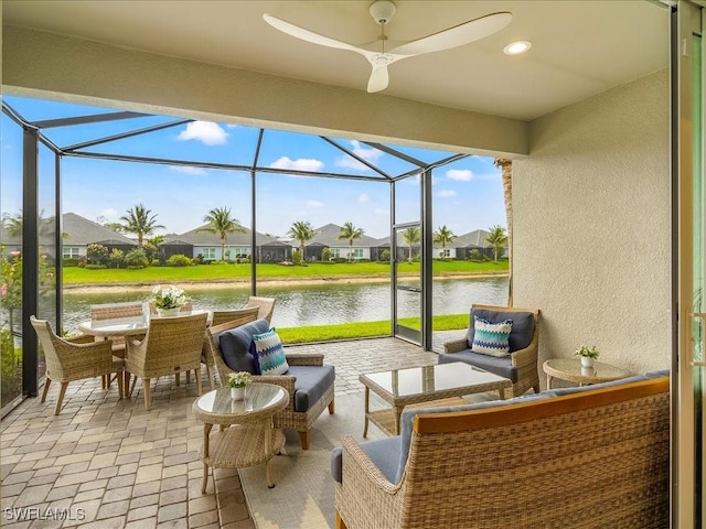 sunroom with plenty of natural light, a water view, a residential view, and ceiling fan