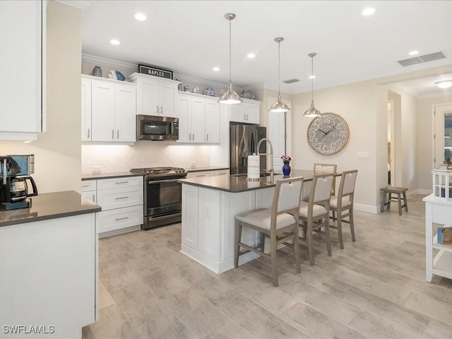 kitchen featuring dark countertops, a kitchen breakfast bar, visible vents, and stainless steel appliances