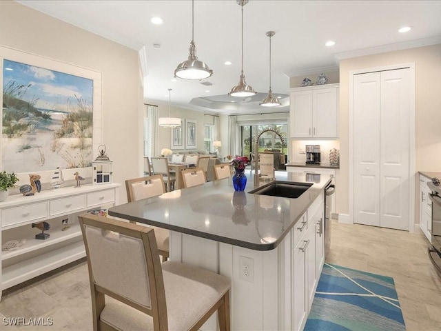 kitchen with a kitchen bar, crown molding, white cabinets, and a sink