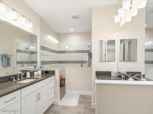 bathroom featuring a sink, two vanities, visible vents, and walk in shower