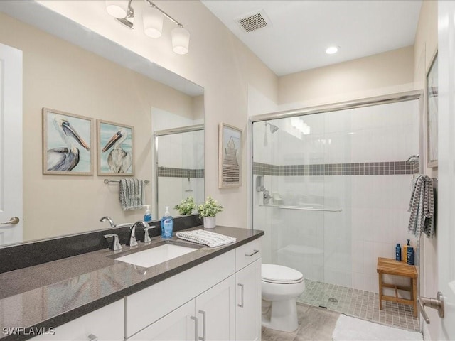 bathroom featuring visible vents, vanity, toilet, and a shower stall