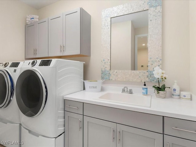 washroom with a sink, cabinet space, and independent washer and dryer