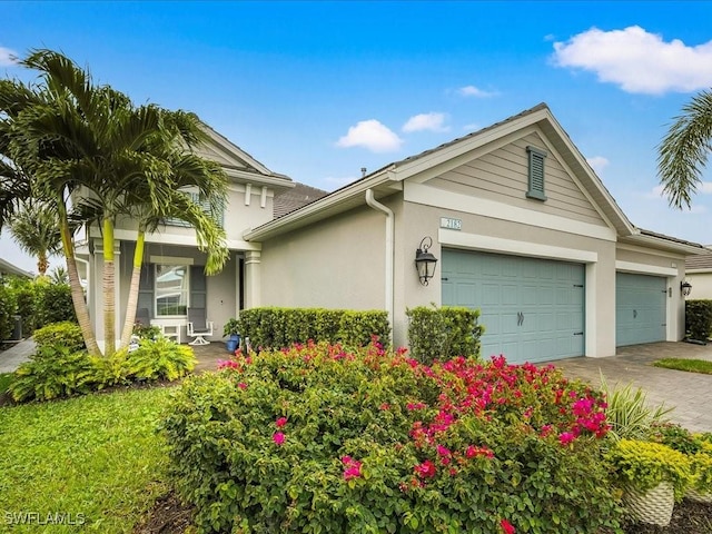 view of side of property featuring stucco siding, decorative driveway, and a garage