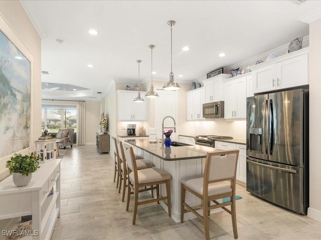 kitchen with a sink, stainless steel appliances, a breakfast bar area, crown molding, and decorative backsplash