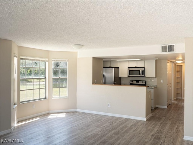 kitchen with baseboards, wood finished floors, visible vents, and stainless steel appliances