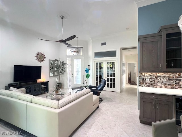 living area featuring visible vents, a ceiling fan, french doors, crown molding, and baseboards