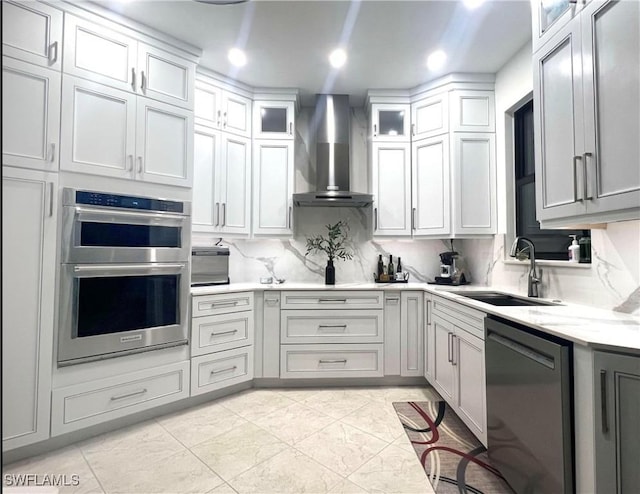 kitchen featuring a sink, backsplash, stainless steel double oven, wall chimney range hood, and dishwasher